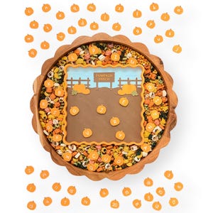 May include: A round wooden scalloped tray filled with colorful pasta shapes and small orange pumpkin-shaped tokens featuring letters and numbers. A square brown mat with a pumpkin patch illustration and the text PUMPKIN PATCH sits in the center.