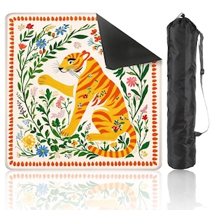 May include: A decorative yoga mat featuring a vibrant tiger illustration in orange and yellow, surrounded by colorful flowers and green foliage. The mat has a cream-colored background with a black underside and comes with a black carrying bag.