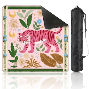 Peut inclure: Un tapis de yoga rose avec un motif de tigre rose à rayures rose foncé, entouré d'illustrations florales et botaniques. Comprend un sac de transport noir avec fermeture à cordon.