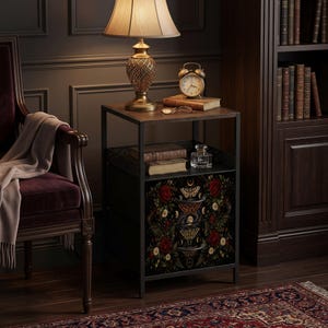 May include: A dark metal nightstand with two drawers featuring a botanical and moth print. The nightstand has a square top surface, an open middle shelf, and a black frame. The drawer fronts display red roses, white daisies, and moths.