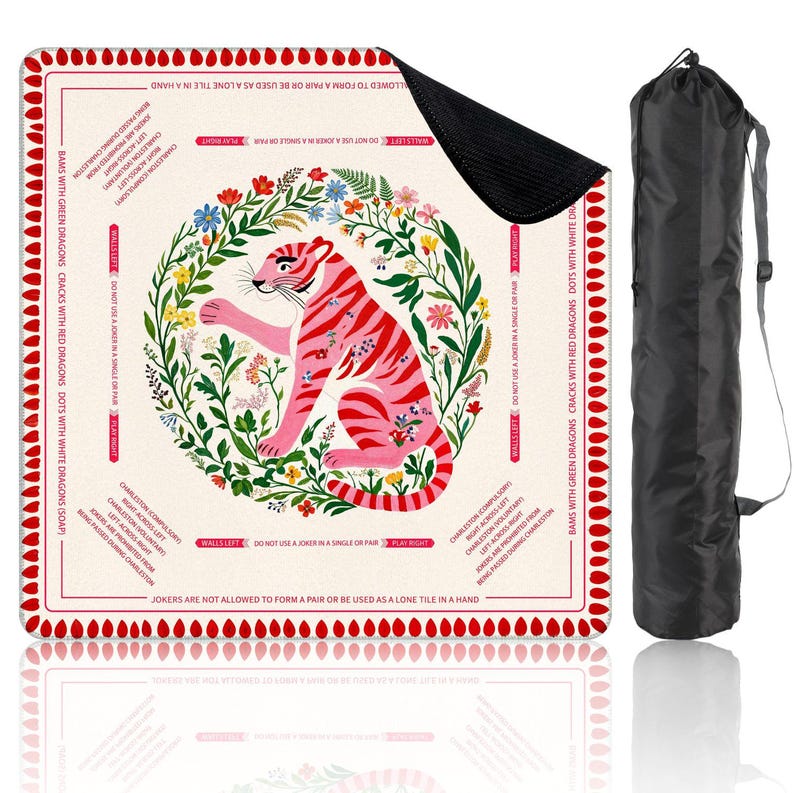 Peut inclure: Un tapis de jeu carr&eacute; avec une illustration de tigre rose entour&eacute;e d'une couronne florale. Le tapis a une bordure rouge avec du texte et est accompagn&eacute; d'un sac de transport noir. Le tapis est con&ccedil;u pour un jeu.