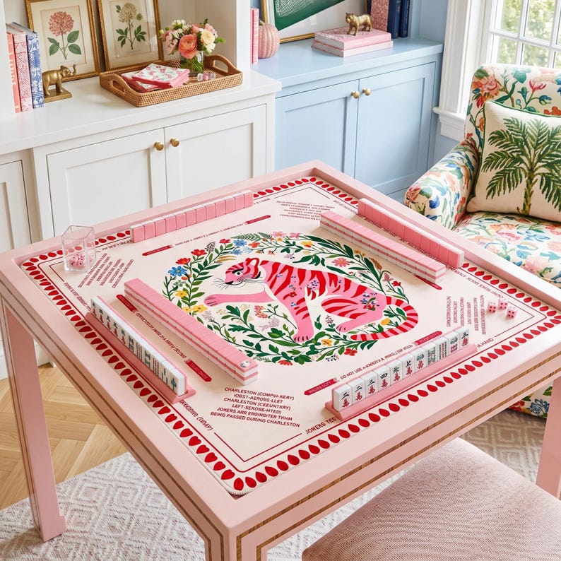 Peut inclure: Une table de mahjong rose avec un motif floral et un tigre. La table a des tuiles et des d&eacute;s roses. La table est carr&eacute;e et a un cadre rose avec une bordure dor&eacute;e. La table est pr&ecirc;te pour un jeu.