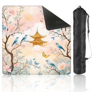 Puede incluir: Una esterilla de yoga con un dise&ntilde;o de inspiraci&oacute;n asi&aacute;tica que presenta una pagoda dorada, p&aacute;jaros azules, mariposas y flores de cerezo. La esterilla va acompa&ntilde;ada de una bolsa de transporte negra con correa para el hombro. Dimensiones no visibles.