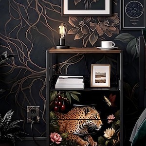 May include: A black metal shelf unit with a wooden top, holding a lamp, books, and a framed picture. The bottom shelf features a leopard design with flowers and a butterfly. The background has a dark floral wallpaper.