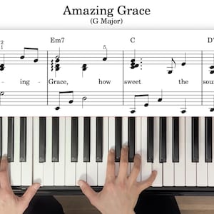 Op de afbeelding: Muziekblad voor "Amazing Grace" in G groot, met pianotoetsen eronder zichtbaar. De titel staat bovenaan en de muzieknoten worden op de notenbalk weergegeven. De pianotoetsen zijn zwart en wit en handen spelen piano.