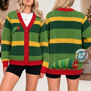 Könnte beinhalten: Eine langärmelige Strickjacke mit horizontalen Streifen in Dunkelgrün, Hellgrün und Gelb. Das Kleidungsstück hat eine rote V-Ausschnitt-Knopfleiste und rote Bündchen. Eine gestickte grüne Raupe mit rotem Kopf befindet sich auf Brust und Rücken.