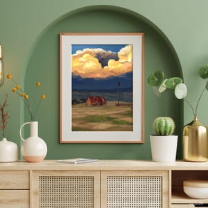 Puede incluir: Impresi&oacute;n art&iacute;stica enmarcada que presenta una escena rural con un granero, un molino de viento y un campo bajo un cielo dram&aacute;tico. La obra de arte muestra una vibrante puesta de sol con nubes doradas y anaranjadas, sobre un fondo azul oscuro.