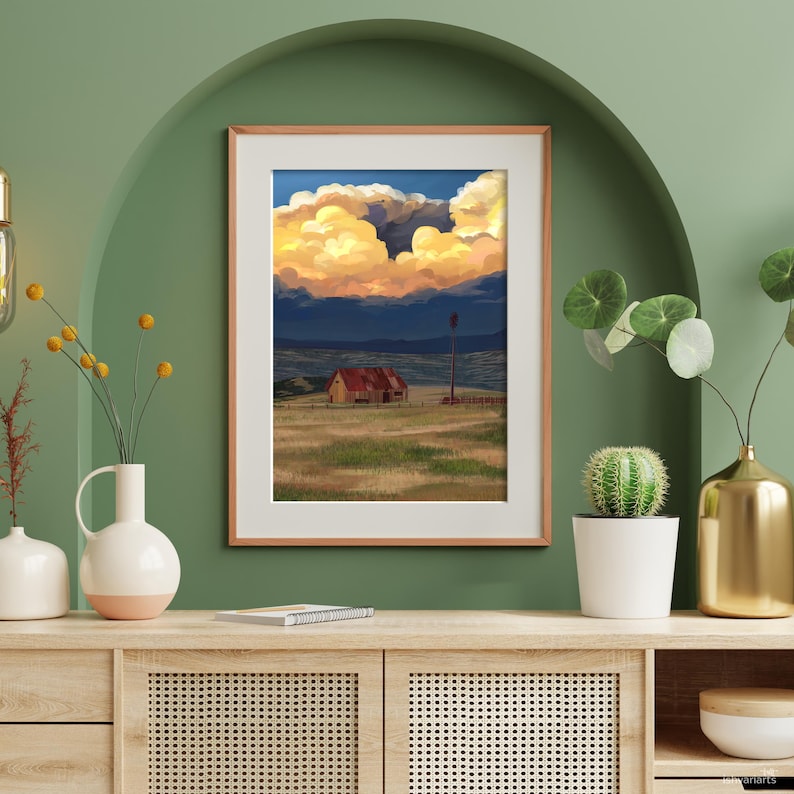 Puede incluir: Impresi&oacute;n art&iacute;stica enmarcada que presenta una escena rural con un granero, un molino de viento y un campo bajo un cielo dram&aacute;tico. La obra de arte muestra una vibrante puesta de sol con nubes doradas y anaranjadas, sobre un fondo azul oscuro.