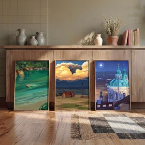 Puede incluir: Tres impresiones art&iacute;sticas enmarcadas con escenas de paisajes. Una representa a una persona nadando en agua verde, otra una puesta de sol sobre un campo con un granero y la tercera un paisaje urbano nocturno con una iglesia.