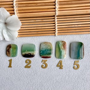 May include: Five rectangular polished gemstones with green, blue, and brown marbled patterns arranged in a row. Each stone is labeled with a gold-colored number from one to five. The stones display varied color gradients and natural mineral inclusions.