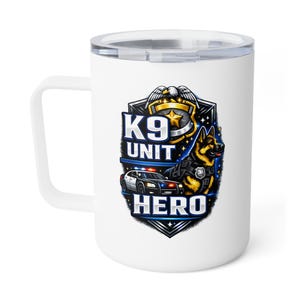 May include: White travel mug with a handle and a clear lid. The mug features a graphic of a German Shepherd dog in a police vest, a police car, and the words "K9 UNIT HERO" in a shield design.