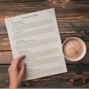 Może przedstawiać: Notatnik "Session Prep Page" z białą okładką i szarym tekstem, obok białego kubka kawy. Notatnik zawiera podpowiedzi dotyczące przeglądu klienta, skupienia, intencji i wskaz&oacute;wek. Tło to ciemna drewniana powierzchnia.