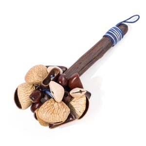 May include: A handmade percussion instrument, a maraca, featuring a dark wooden handle wrapped with blue and white string. The shaker head is filled with various seeds and nuts in shades of brown and beige.