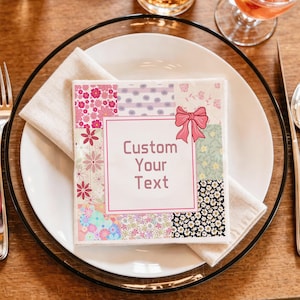 Puede incluir: Una servilleta de papel cuadrada con un diseño de patchwork de varios patrones florales en tonos rosa, azul, amarillo y negro. Un lazo rosa está ilustrado en la esquina superior derecha, y el centro contiene un recuadro con borde rosa con el texto Custom Your Text.