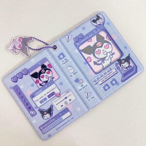 May include: A light blue, bi-fold card holder featuring a cartoon character design. The design includes hearts, computer-themed graphics, and the text "My Favorite.psd". A matching charm is attached with a chain. The card holder is decorated with the text "Too cute to Deleted:(".