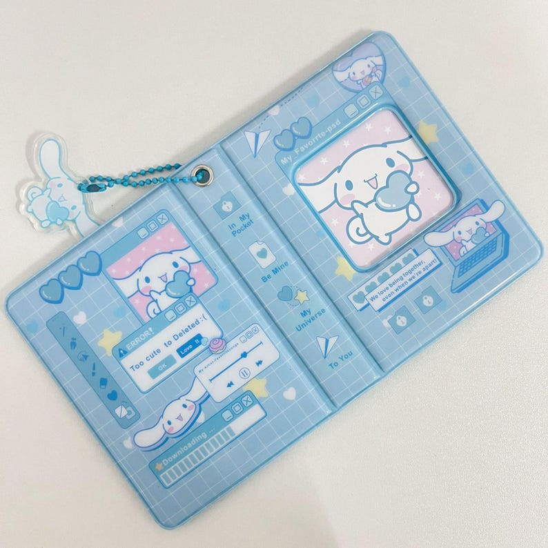 May include: A light blue, bi-fold card holder with a cartoon bunny design. The holder features a clear plastic overlay with various graphics, including hearts, computer windows, and the text "My Favorite-psd". A matching bunny charm hangs from a chain.