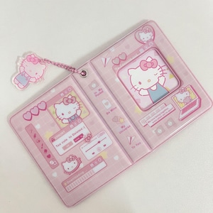 May include: Pink Hello Kitty themed notebook with a matching charm. The notebook features multiple Hello Kitty illustrations and text boxes with phrases like "In My Pocket" and "Be Mine". The charm is a small, transparent Hello Kitty figure.