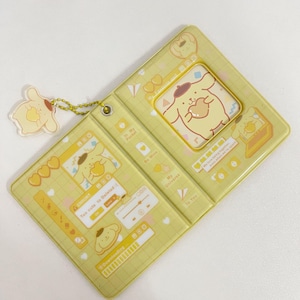 May include: A yellow, hinged case with a cartoon dog design. The case has a matching dog charm attached. The design includes hearts, text, and a music player interface. The text includes "Too cute to Deleted :(" and "Downloading".