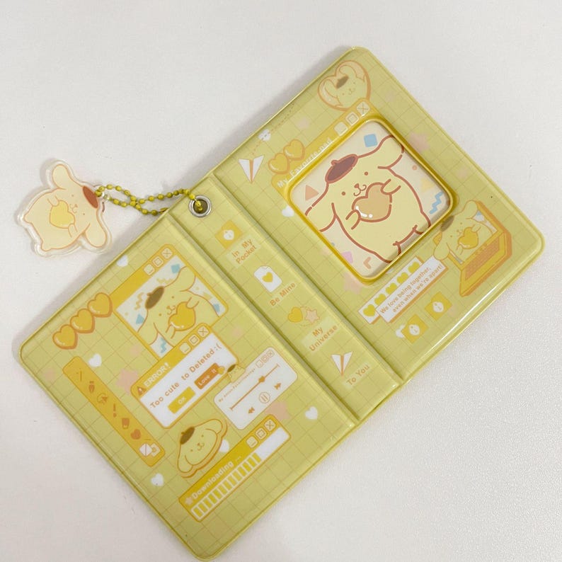 May include: A yellow, hinged case with a cartoon dog design. The case has a matching dog charm attached. The design includes hearts, text, and a music player interface. The text includes "Too cute to Deleted :(" and "Downloading".