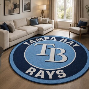 May include: A circular area rug featuring the Tampa Bay Rays baseball team logo. The design includes a dark blue outer ring, a light blue inner circle, and the white TB monogram in the center with the text TAMPA BAY RAYS printed in white.