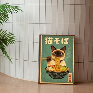 May include: A framed poster featuring a Siamese cat enjoying ramen noodles. The cat, with blue eyes and a black mask, is holding chopsticks. The poster has Japanese text and a vintage aesthetic, with a teal background and a brown frame.