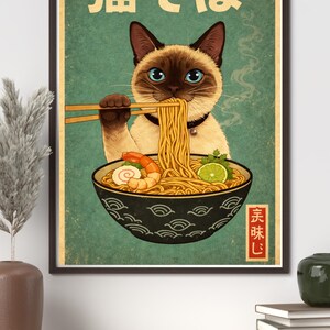 May include: A framed vintage-style poster featuring a Siamese cat enjoying ramen. The cat, with blue eyes, holds chopsticks with noodles. The bowl contains shrimp, lime, and other ingredients. Japanese text is at the top and bottom.