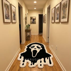 May include: A black and white rug in the shape of a Scream mask, placed on a wooden floor in a hallway. The rug has a white border with a dripping effect. The hallway has framed photos on the walls.