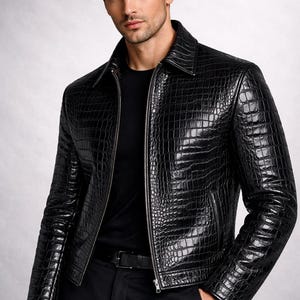 Peut inclure: Veste en cuir noir avec une texture peau de crocodile. La veste a une fermeture éclair, un col et des manches longues. La personne porte une chemise noire et un pantalon noir. Vêtement d'extérieur élégant.
