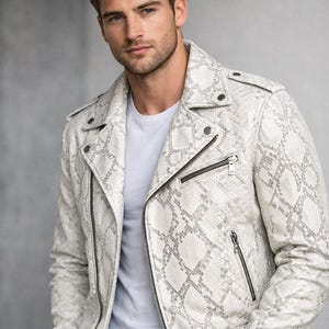 May include: A white and gray snakeskin-patterned leather jacket with a zipper closure and silver hardware. The jacket has a classic biker style with a notched collar and snap details. The person is wearing a white t-shirt underneath.