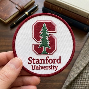 May include: A round, white patch with a red border featuring the Stanford University logo. The logo includes a stylized red "S" with a green pine tree inside, and the words "Stanford University" in red.