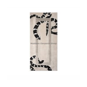 May include: A rectangular beige rug with a geometric design featuring black and white snake-like patterns. The rug has a rectangular frame in a lighter beige colour. The text "Modern Carpets Shop" is visible.