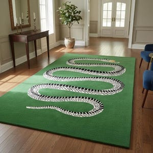 May include: A green rectangular rug with a large snake design in white and black. The snake winds across the rug. The rug is in a room with hardwood flooring and blue chairs. The rug's dimensions are approximately 240 cm x 300 cm.