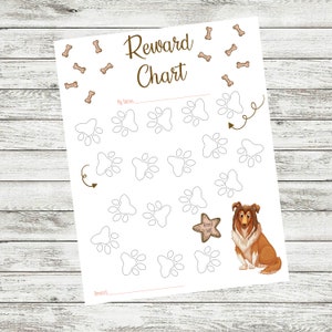 Op de afbeelding: Een witte beloningskaart met pootafdrukken en botillustraties. De woorden "Reward Chart" staan bovenaan, met ruimte voor een naam en beloningen. Een cartoon collie hond en een stervormige beloning zijn ook afgebeeld.