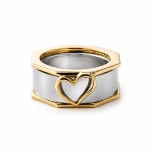 Puede incluir: Un anillo de dos tonos con una banda ancha de color plateado y acabado pulido. El anillo está enmarcado por un borde hexagonal de color dorado en los bordes superior e inferior. Un recorte en forma de corazón dorado está centrado al frente.