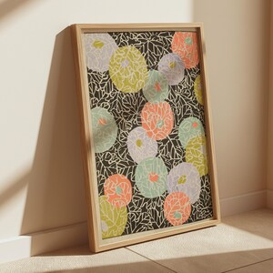 Può includere: Una stampa artistica incorniciata con un motivo floreale. Il design presenta forme di fiori circolari colorate in tonalità di giallo, arancione, viola e verde su uno sfondo nero con dettagli bianchi a forma di foglia. La cornice è in legno chiaro.