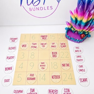 May include: A grid board with numbered squares and circular tags labelled with items like stationary pack, plush, and jewellery item. A multi-coloured crystal-shaped object sits in the corner with a small red die. The board features the NBP BUNDLES logo.