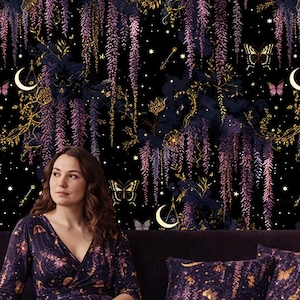 May include: A woman sits on a purple velvet sofa with matching pillows and a rug. The background is a dark floral wallpaper with gold accents, butterflies, and crescent moons. The woman wears a long-sleeved dress with a similar pattern.