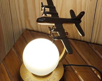 Lámpara de mesa metálica con forma de avión y luz esférica. Iluminación de escritorio con forma de avión.