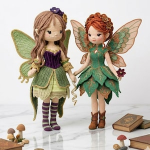 May include: Two handmade crochet fairy dolls. One doll has brown hair, a purple bodice, and a green skirt. The other doll has red hair and a green leaf-like dress. Both dolls have large, detailed wings and are holding hands.