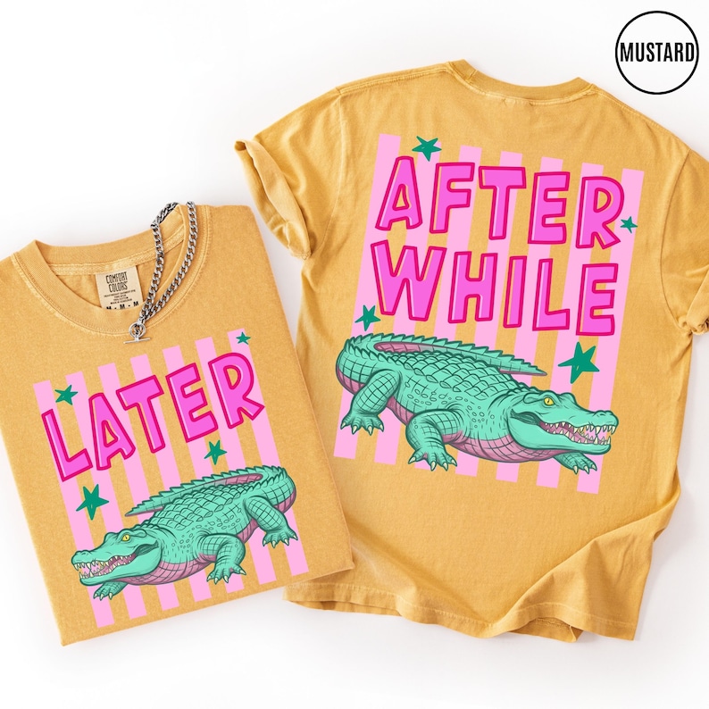 Puede incluir: Camisetas de color mostaza con las frases "LATER" y "AFTER WHILE" en letras rosas. Cada camiseta presenta un gr&aacute;fico de un caim&aacute;n verde. Rayas verticales rosas y estrellas verdes acent&uacute;an el texto y el caim&aacute;n.
