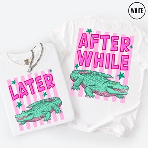 Puede incluir: Dos camisetas blancas con fondos a rayas rosas y textos rosas &laquo;LATER&raquo; y &laquo;AFTER WHILE&raquo;. Cada camiseta presenta una ilustraci&oacute;n de un caim&aacute;n verde. Estrellas verdes est&aacute;n dispersas alrededor del texto y del caim&aacute;n.