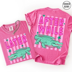 May include: Two pink t-shirts with the words "LATER" and "AFTER WHILE" in pink block letters. Each shirt features a green alligator graphic and green star accents. The shirts are made of a soft, comfortable material.