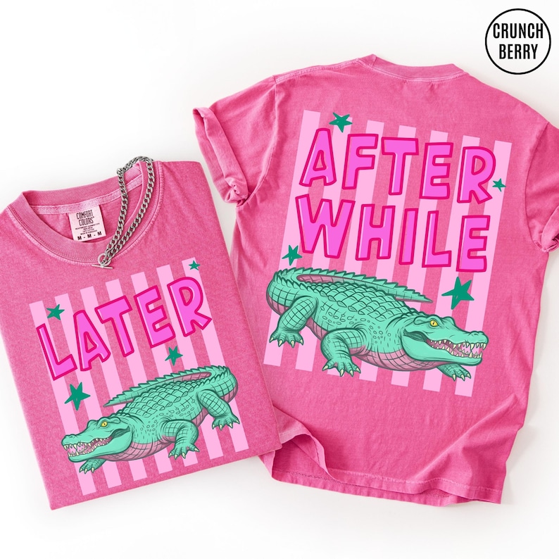 Puede incluir: Dos camisetas rosas con las palabras "LATER" y "AFTER WHILE" en letras rosas. Cada camiseta presenta un gr&aacute;fico de caim&aacute;n verde y acentos de estrellas verdes. Las camisetas est&aacute;n hechas de un material suave y c&oacute;modo.