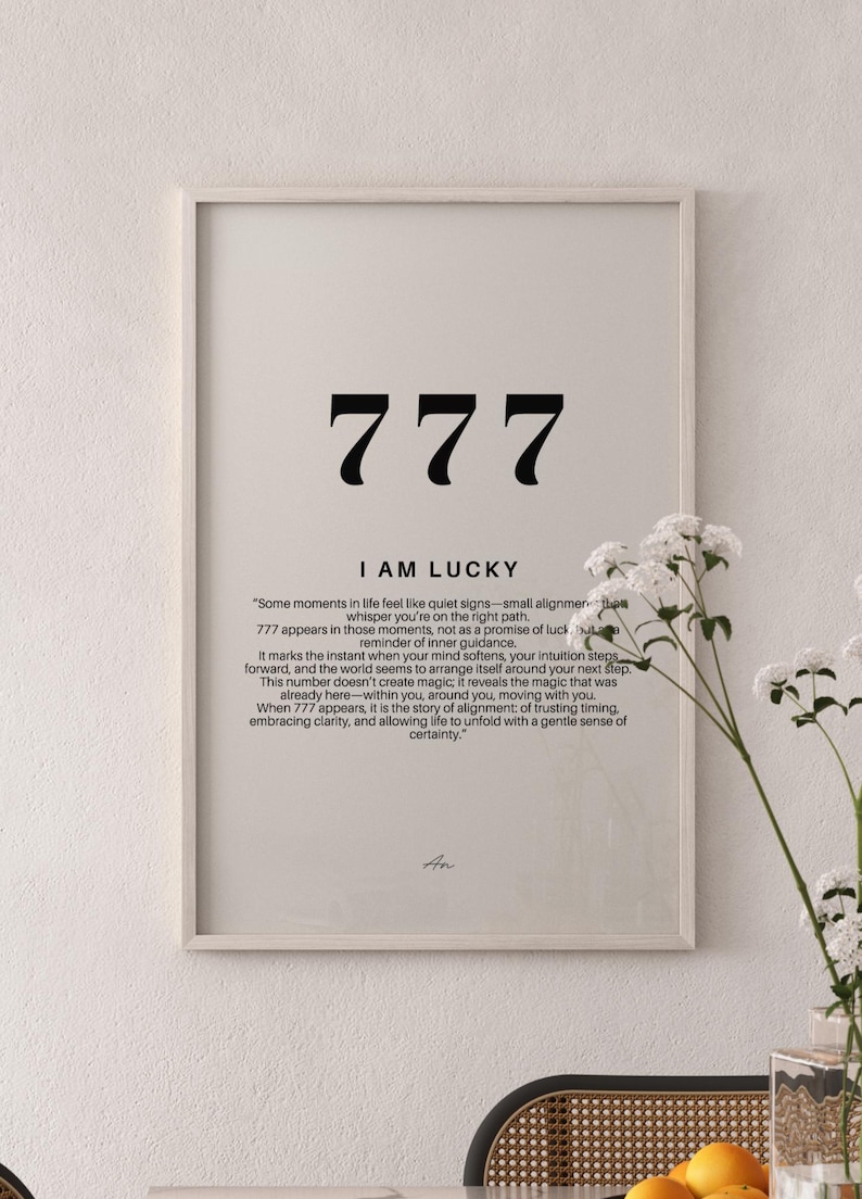 May include: A framed wall art print featuring the number 777 in large black font, the text I AM LUCKY, and a paragraph explaining the significance of the number. The design is printed on a light beige background within a light wood frame.