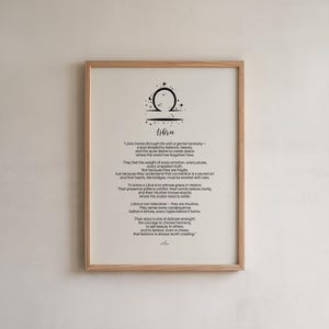 May include: A framed print featuring the Libra zodiac symbol and a description of Libra's characteristics. The print has a light wood frame and a white background with black text. The Libra symbol is at the top.