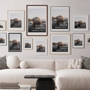 K&ouml;nnte beinhalten: Eine Galerie-Wand mit zw&ouml;lf rechteckigen Glasrahmen in verschiedenen Gr&ouml;&szlig;en, darunter 50x76, 46x61, 41x51, 41x41, 30x46, 51x51, 28x36, 30x41, 23x30, 22x28, 20x25 und 13x18 cm, die jeweils eine Landschaftsaufnahme eines Felsens im Wasser zeigen.
