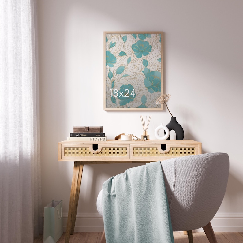 May include: A rectangular wall art print in a light wood frame featuring a teal floral pattern with gold line accents and the text 18x24. The artwork is displayed above a light wood console table with cane drawer fronts and a light blue throw.