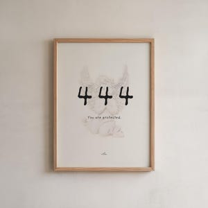 May include: Framed art print featuring a sketch of an angel with wings, the number 444 in black, and the text "You are protected." The artwork is in a light wood frame, suitable for wall decor.