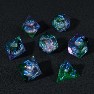 May include: Set of seven polyhedral dice in various shapes, including a d20, d12, d10, d8, d6, and d4. The dice are transparent with a colorful, iridescent interior and blue numbering. The dice are designed for tabletop role-playing games.