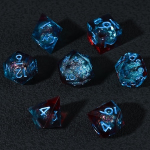 Puede incluir: Juego de siete dados poliédricos transparentes azules con detalles rojos y purpurina. Cada dado tiene números blancos. Adecuado para juegos de rol. Los dados están colocados sobre una superficie oscura.